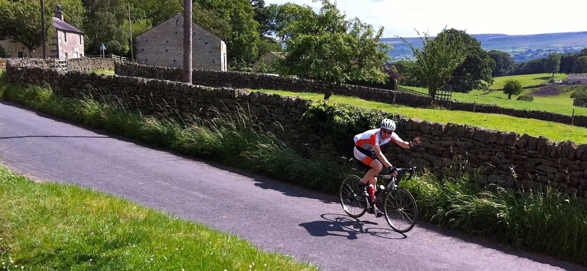 a photo of a man waving on a bike