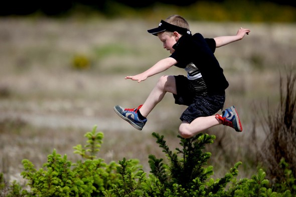 Boy Running Through a Field Jumping and Having Fun