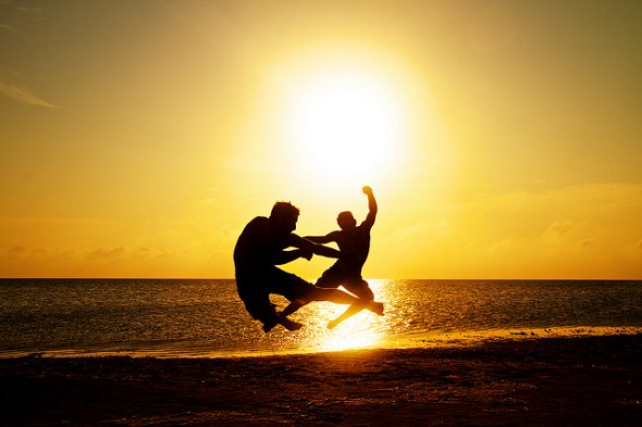 Two people on the beach jumping making ninja poses