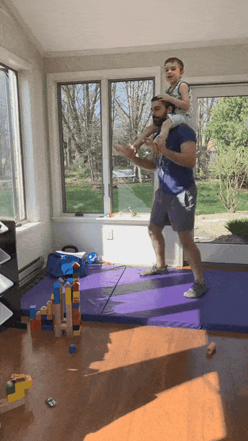 Matt has his kiddo resting on his shoulders, almost like a safety squat bar would.