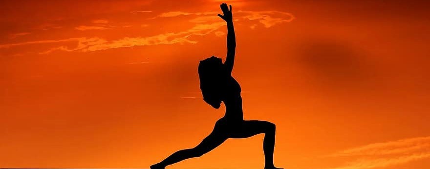 A woman against the sunset doing a lunge variation.