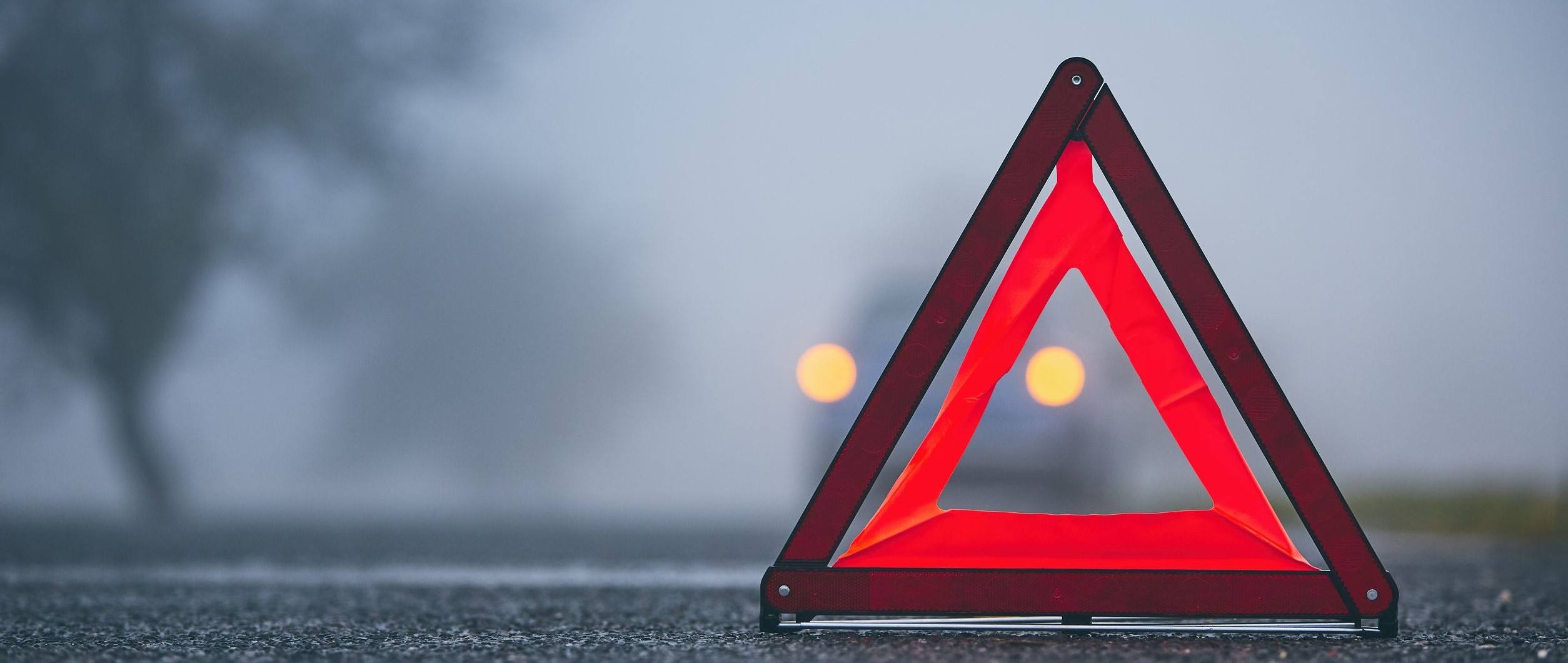 A Warning Triangle on a road with a car in the background.