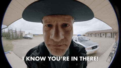 A Police Officer at the door saying Someone saying "I Know You're In There"