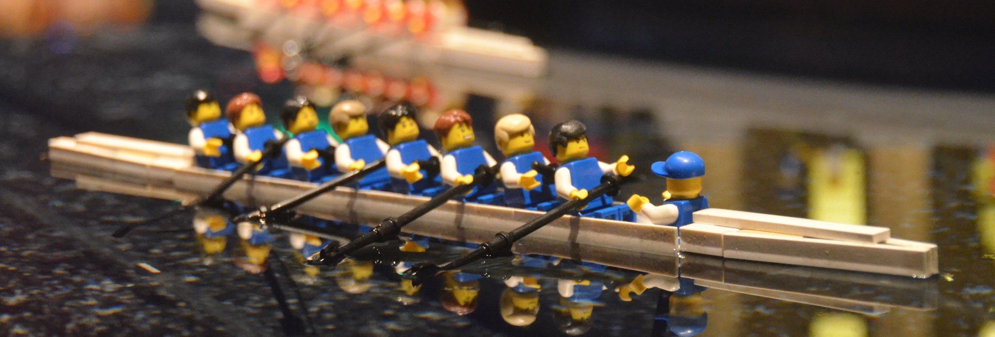 Team of Lego men rowing a boat