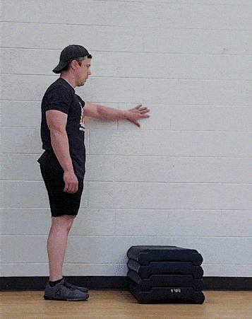 Coach Jim doing an assisted step-up, by holding on to a nearby wall.