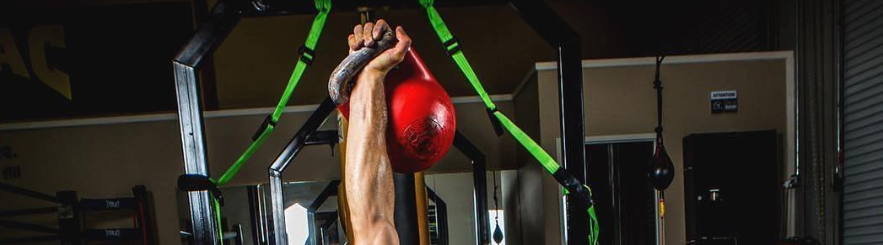 A hand holding up a kettlebell 